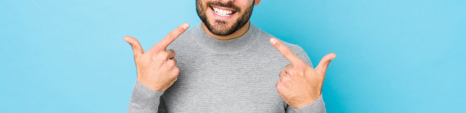 dogodki/young-caucasian-man-against-blue-wall-smiles-pointing-fingers-mouth_1