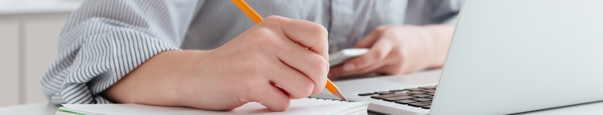 tecaji/young-smiling-woman-striped-shirt-taking-notes-while-sitting-table-light-apartment